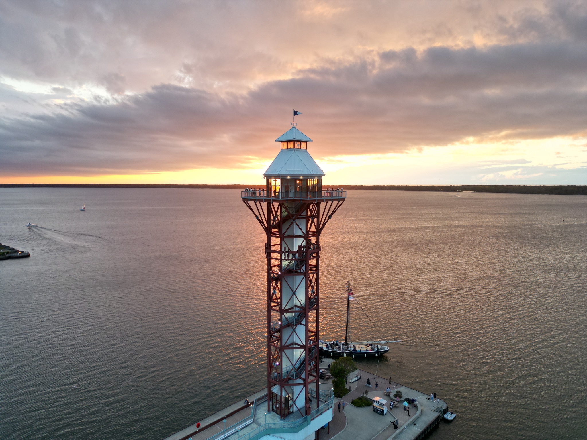 Floatography aerial photograph of a waterfront observation tower against a glowing sunset over the bay